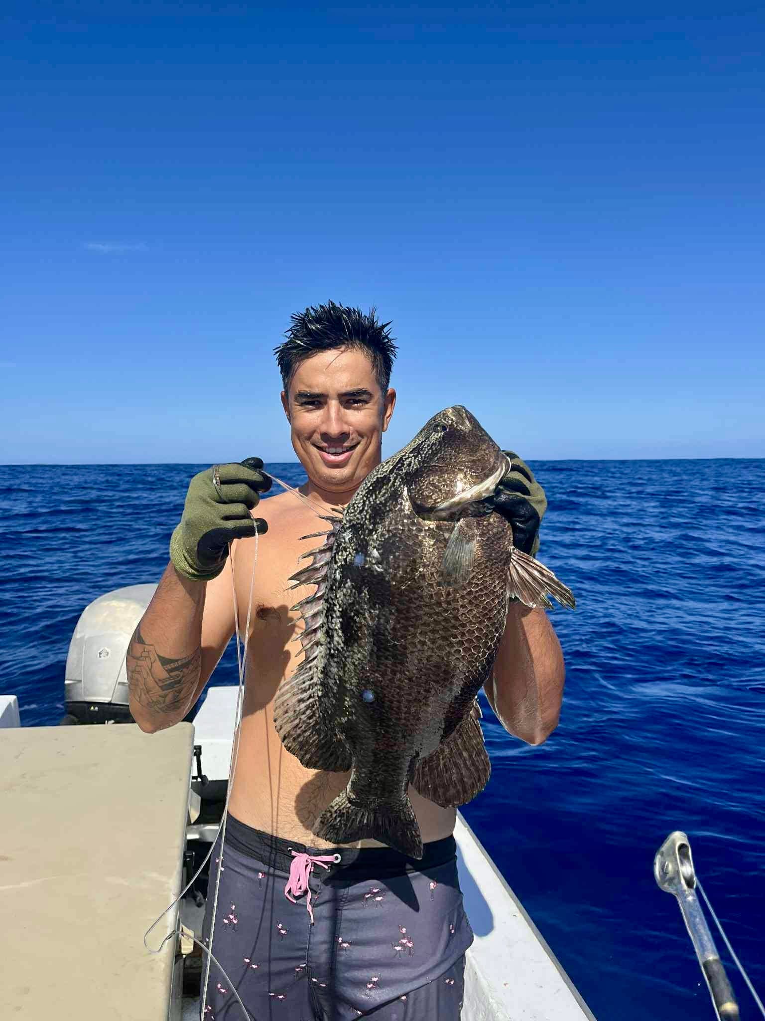 Fishing: Angler with a grouper caught over the reef